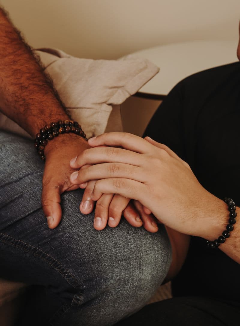 Two people's hands resting together in a quiet moment of support